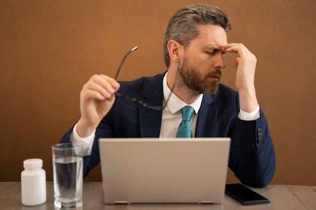 El hombre de negocios siente dolor sosteniendo gafas frotando los ojos secos e irritados fatigados por el estrés laboral de la computadora