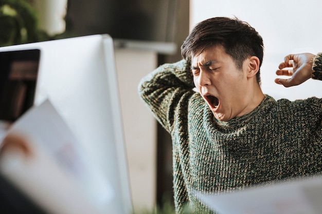 Hombre de negocios soñoliento bostezando en la oficina