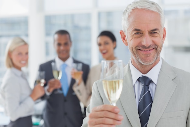 Hombre de negocios sonriendo a la cámara con champán