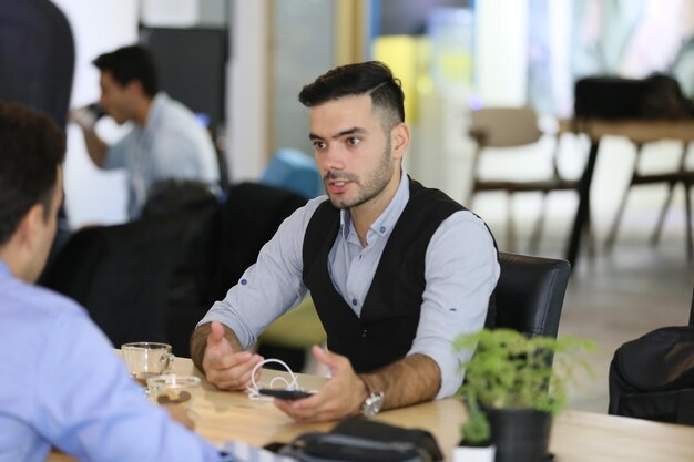 Un hombre de negocios sonriente y un colega hablando mientras están sentados en la mesa.