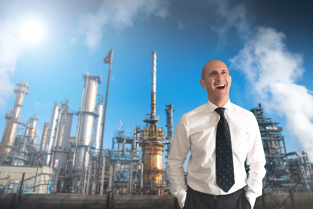 Hombre de negocios sonriente con detrás de una refinería