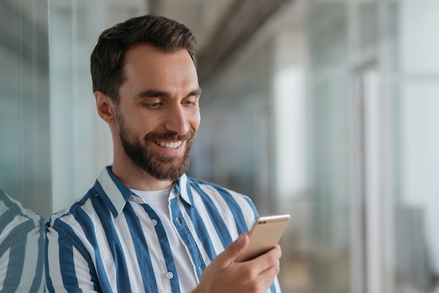 Hombre de negocios sonriente hermoso que usa la comunicación del teléfono móvil en línea