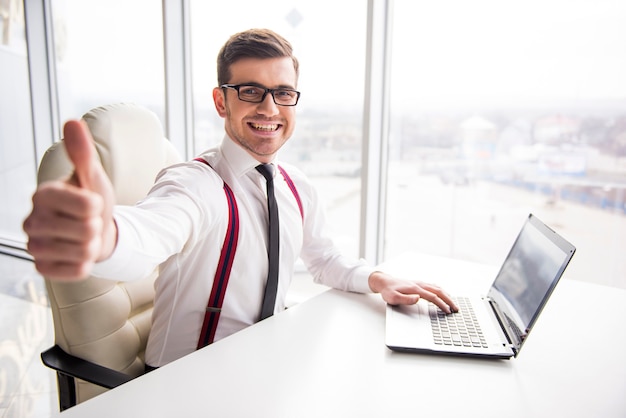 El hombre de negocios sonriente joven está mostrando el pulgar para arriba