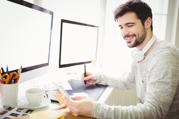 Hombre de negocios sonriente que usa la tableta gráfica en el escritorio