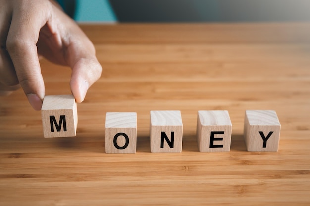 El hombre de negocios sostiene un bloque de madera con el concepto de dinero y finanzas de texto de dinero