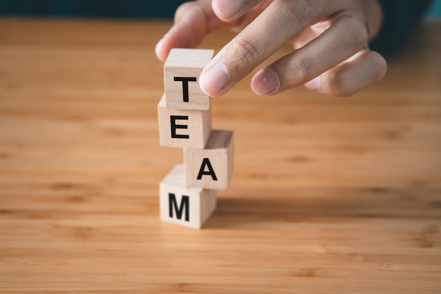 El hombre de negocios sostiene un bloque de madera con el concepto de organización y trabajo en equipo de Team text