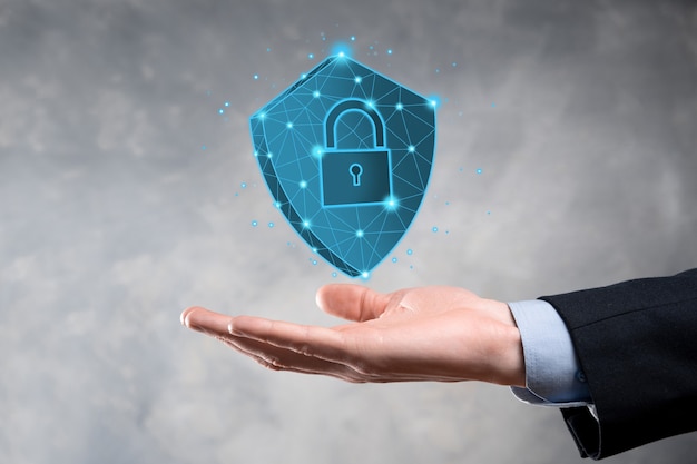El hombre de negocios sostiene un escudo poligonal bajo con un icono de candado.Concepto de sistema de acceso seguro.Garantía financiera empresarial para la inversión.Concepto antivirus.Seguridad tecnológica.Red de protección, datos seguros.