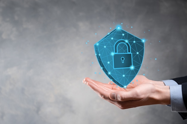El hombre de negocios sostiene un escudo poligonal bajo con un icono de candado.Concepto de sistema de acceso seguro.Garantía financiera empresarial para la inversión.Concepto antivirus.Seguridad tecnológica.Red de protección, datos seguros.