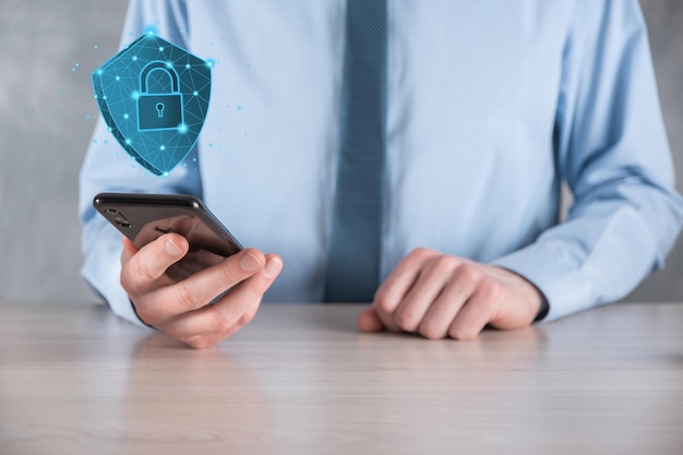 El hombre de negocios sostiene un escudo poligonal bajo con un icono de candado.Concepto de sistema de acceso seguro.Garantía financiera empresarial para la inversión.Concepto antivirus.Seguridad tecnológica.Red de protección, datos seguros.