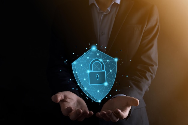 El hombre de negocios sostiene un escudo poligonal bajo con un icono de candado.Concepto de sistema de acceso seguro.Garantía financiera empresarial para la inversión.Concepto antivirus.Seguridad tecnológica.Red de protección, datos seguros.