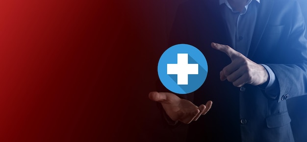 El hombre de negocios sostiene el ícono más, el hombre sostiene en la mano ofrece algo positivo como ganancias, beneficios, desarrollo, RSE representado por el signo más. La mano muestra el signo más. Iconos planos con sombras largas.