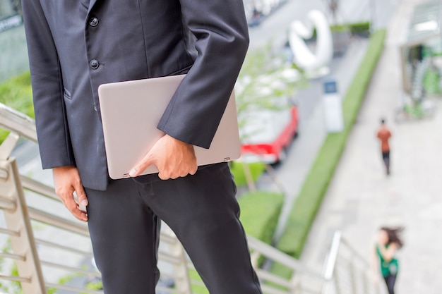 Hombre de negocios con su computadora portátil que sube las escaleras en una hora punta para trabajar. tiempo de prisa