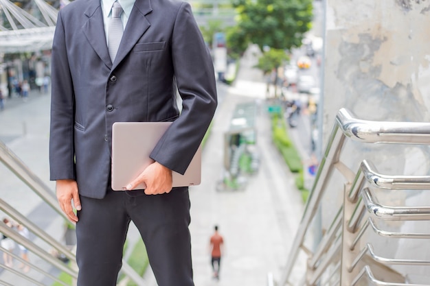 Hombre de negocios con su computadora portátil que sube las escaleras en una hora punta para trabajar. Tiempo de prisa