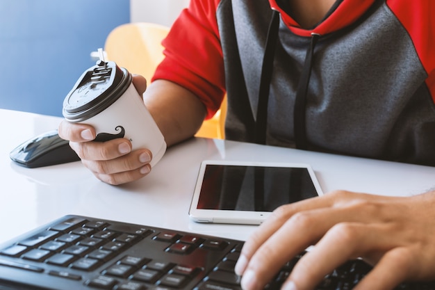 Foto el hombre de negocios y la taza de café de papel en el escritorio está trabajando en la oficina