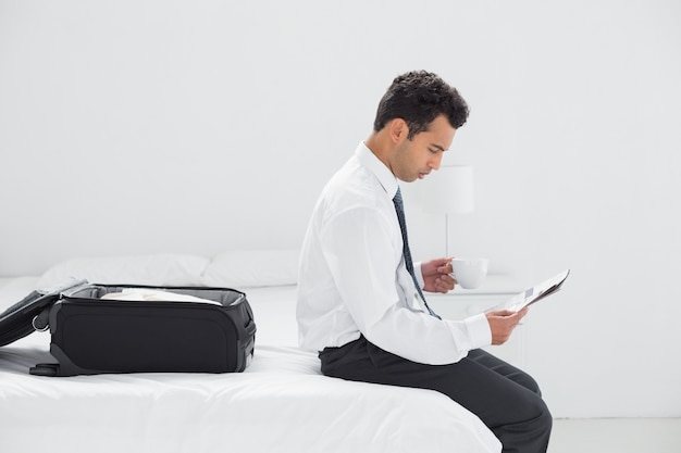 Hombre de negocios con taza leyendo el periódico en la habitación del hotel