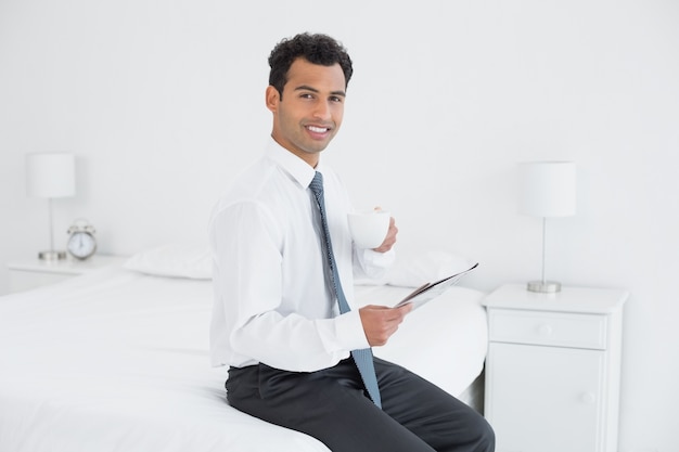 Hombre de negocios con taza leyendo periódico en una habitación de hotel