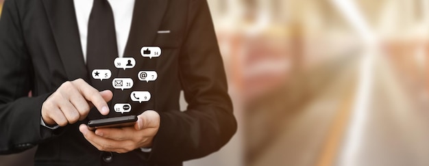 Hombre de negocios con un teléfono inteligente en la mano con el icono de la dirección de correo electrónico del teléfono móvil y el concepto de contacto con el centro de llamadas de servicio al cliente o el uso de las redes sociales