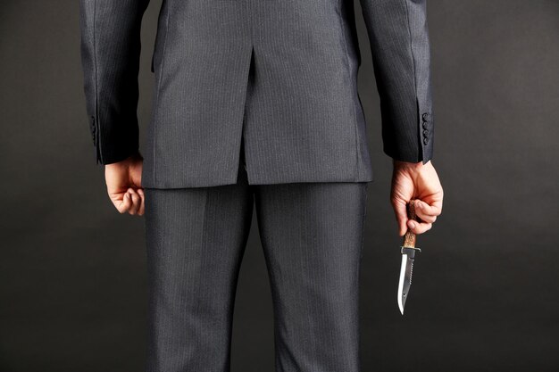 hombre de negocios, tenencia, cuchillo, atrás, el suyo, espalda, en, fondo gris