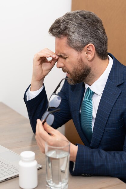 El hombre de negocios tiene migraña toca la cabeza debido al dolor gerente del hombre con fuerte dolor de cabeza trabajando