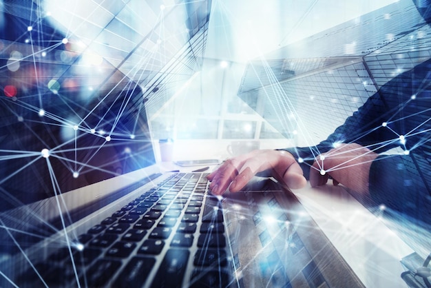 El hombre de negocios trabaja en la oficina con una computadora portátil en primer plano Concepto de trabajo en equipo y asociación doble exposición con efectos de red