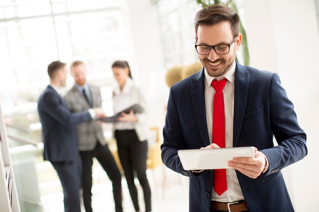 Hombre de negocios trabajador vestido con traje de pie en la oficina moderna y uso de tableta