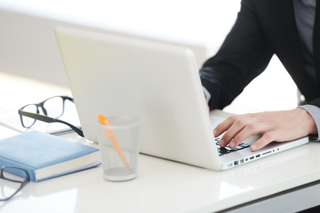 Hombre de negocios trabajando en la computadora portátil, manos escribiendo