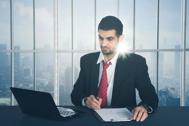 Un hombre de negocios trabajando en un informe de negocios con una computadora portátil en una oficina moderna