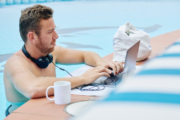 Hombre de negocios trabajando desde la piscina