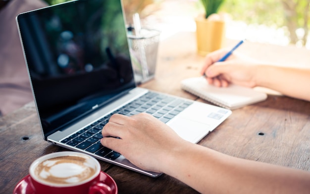 hombre de negocios trabajando con su computadora portátil y tomando café en un escritorio de madera en la cafetería