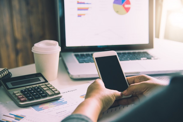 Hombre de negocios trabajando en teléfonos inteligentes y computadoras portátiles en la oficina de espacio abierto