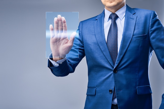 Un hombre de negocios con traje azul pone su mano en un panel de acceso virtual