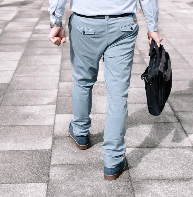 Hombre de negocios con traje de color claro y maletín oscuro que va a trabajar vista trasera