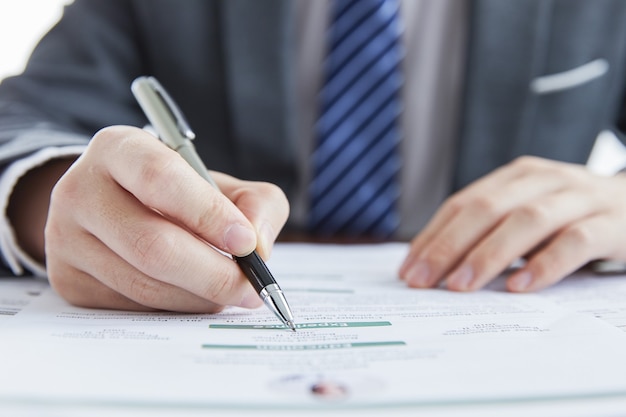 Hombre de negocios en traje elegante en una reunión de negocios firmando contratos en la oficina