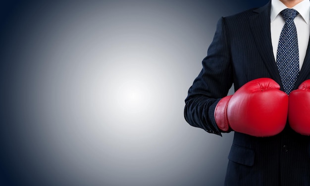 Hombre de negocios en traje gris con guantes de boxeo rojos