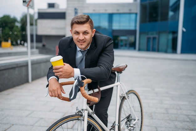 Hombre de negocios en traje con maletín y bicicleta en el centro. Persona de negocios en transporte ecológico en las calles de la ciudad