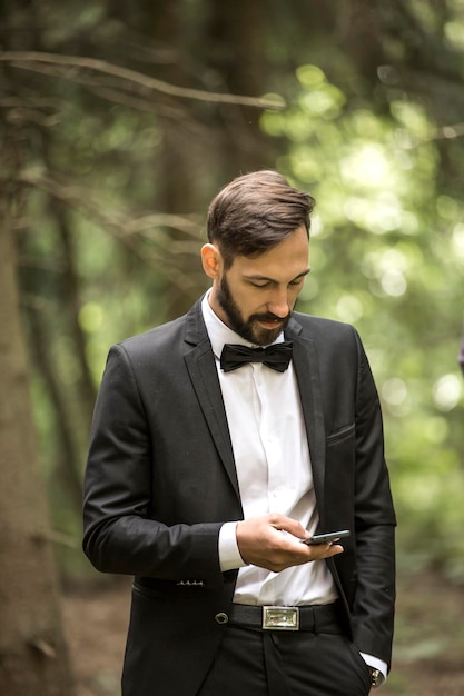 Hombre de negocios en traje de negocios con un teléfono inteligente en el fondo del parque