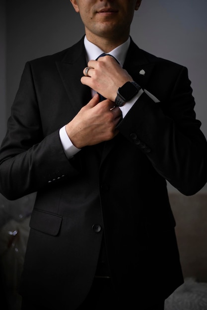 Hombre de negocios con traje negro y ajustando su corbata