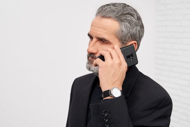 Hombre de negocios en traje negro hablando por teléfono.