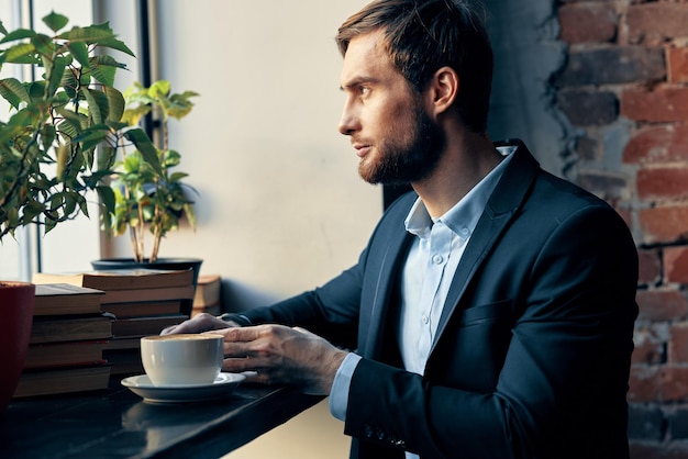 Hombre de negocios con traje sentado en una mesa con una taza de café en un descanso de café