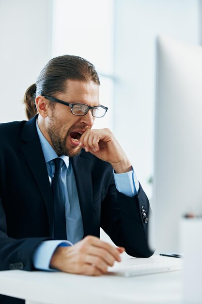 Foto hombre de negocios en un traje sentado en su escritorio cansado frente a una computadora