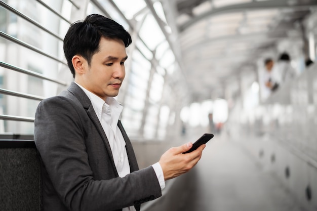 Hombre de negocios en traje con smartphone en la ciudad