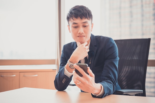 Hombre de negocios en traje y con smartphone moderno en su oficina. concepto para negocio