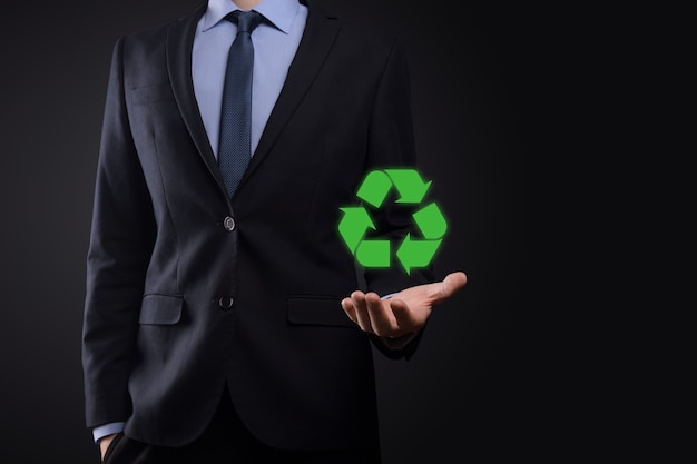 Hombre de negocios en traje sobre fondo oscuro tiene un icono de reciclaje
