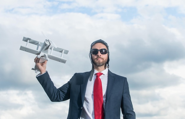 Foto hombre de negocios con traje y sombrero de piloto lanzando avión concepto de viaje de negocios de juguete