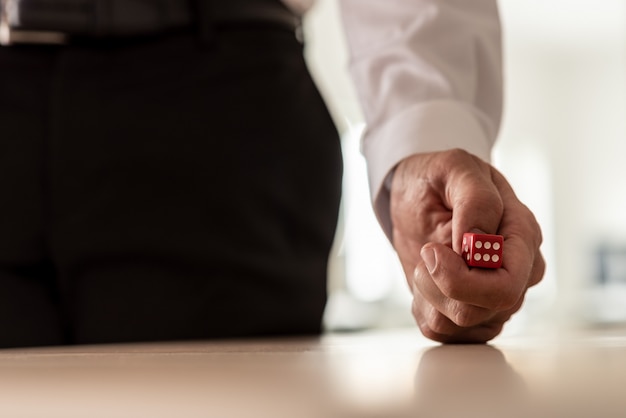 Hombre de negocios en traje tirando dados rojos