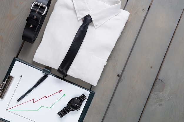 Foto hombre de negocios, traje de trabajo sobre fondo de madera gris. camisa blanca con corbata negra, cinturón, planchette. volver al trabajo. conjunto de mans moda y complementos. copia espacio, marco.