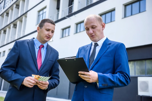 Hombre de negocios en trajes hacer trato con los billetes en euros