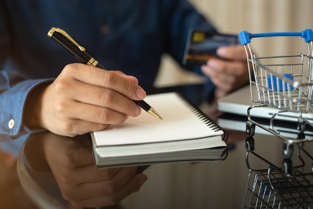 Hombre de negocios usa una computadora portátil y toma notas en el cuaderno en el escritorio de la oficina