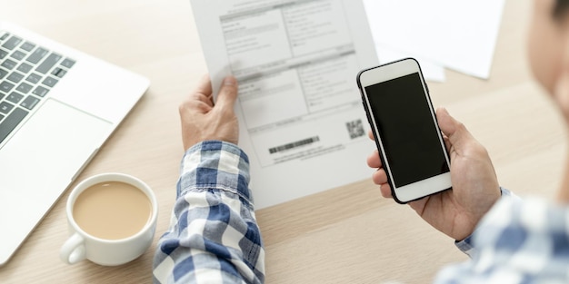 Foto el hombre de negocios usa el teléfono para escanear códigos de barras o códigos qr para pagar la factura de la tarjeta de crédito después de recibir el documento, la factura, el pago en línea, recibir el pago de electricidad, pagos digitales sin tecnología de dinero.