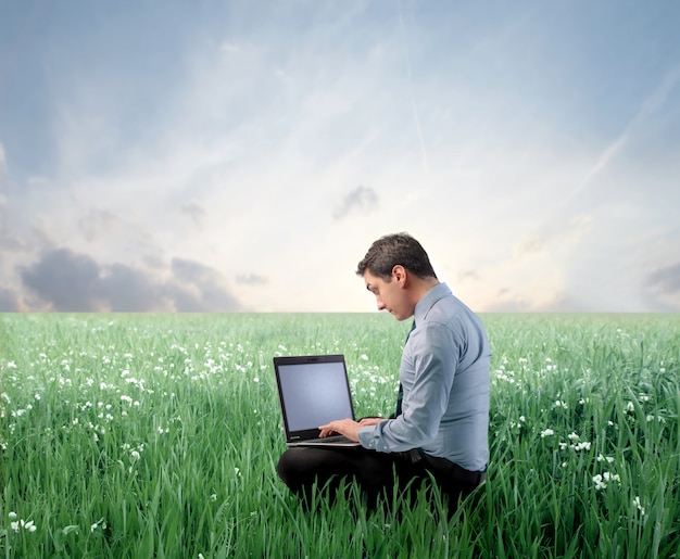 Hombre de negocios usando una computadora portátil en un prado